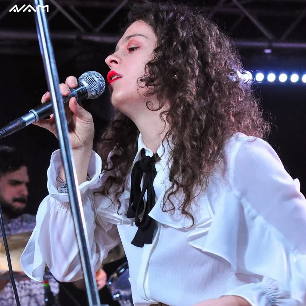 Alessia canta dal vivo su un palco, con il microfono in mano